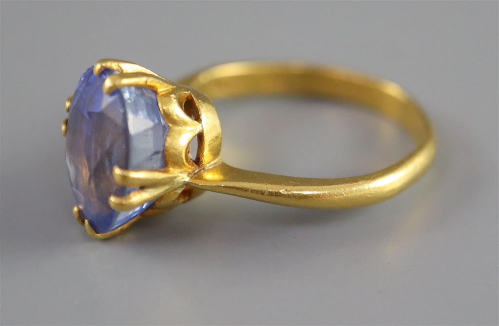 A gold (stamped 24k) and solitaire oval cut Ceylon sapphire set ring,